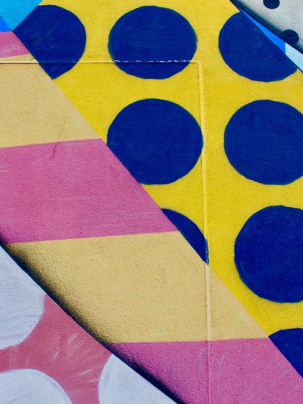 Vibrant geometric wall mural with bold colors and patterns featuring circles and stripes.